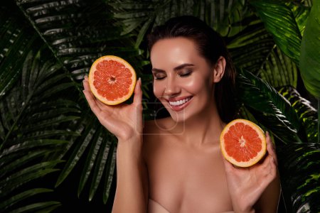 Photo for Photo of seductive pretty lady nude shoulders smiling rising orange halves outdoors tropical resort. - Royalty Free Image