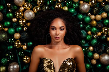 Photo for Studio portrait of attractive mixed race ethnicity young woman laying among new year tree toys festive shine clothes. - Royalty Free Image