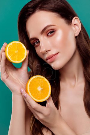 Photo for Vertical photo of cute smiling lady naked shoulders holding two citrus halves isolated green color background. - Royalty Free Image