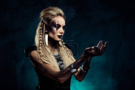 Téléchargez les photos : Photo de femme nécromancien puissant dans la tribu viking faisant magie prédiction de victoire de guerre sur fond de brume. - en image libre de droit