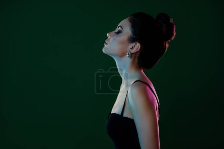 Téléchargez les photos : Photo latérale de calme magnifique dame en robe noire après la date romantique au restaurant isolé sur fond de couleur verte. - en image libre de droit