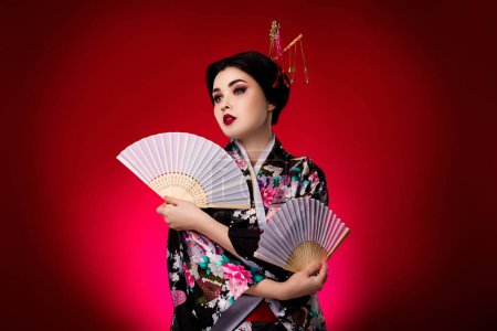 Téléchargez les photos : Photo de dame élégante habillée robe japonaise kimono regardant espace vide isolé sur fond de couleur dégradé rouge. - en image libre de droit