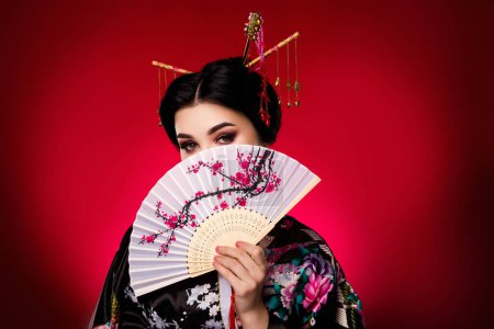 Photo for Photo of korean shy cute lady cover face traditional japanese culture theme festival isolated on red color background. - Royalty Free Image