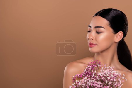 Téléchargez les photos : Portrait de magnifique femme mignonne rêveuse beauté produit naturel crème fleurs parfum isolé sur fond de couleur beige. - en image libre de droit