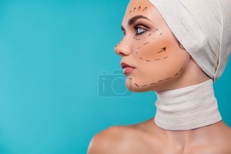 Foto de Foto de una paciente de cirugía plástica con marcas de corrección para el cambio de la cara corporal aislada sobre fondo cian. - Imagen libre de derechos