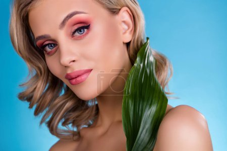 Photo for Photo of chic feminine girl applying organic beauty product lotion with plant extract over blue background. - Royalty Free Image