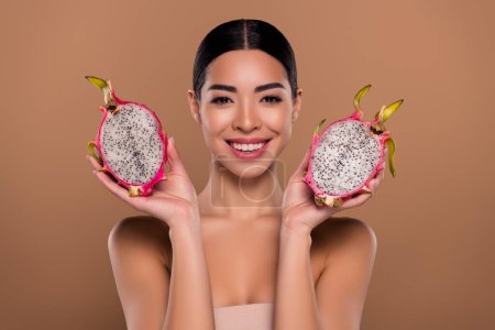 Photo for Portrait of sensual girlfriend holding two halves dragon fruit advertising cosmetics isolated on beige color background. - Royalty Free Image