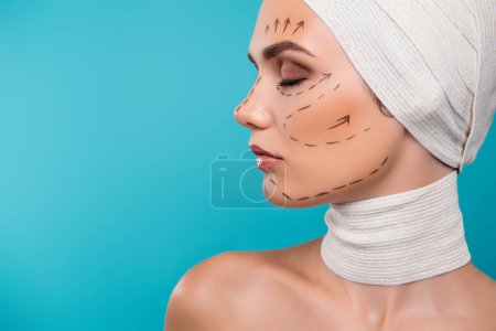 Photo for Photo of attractive lady in medical bandage prepare for beauty plastic operation over cyan color background. - Royalty Free Image