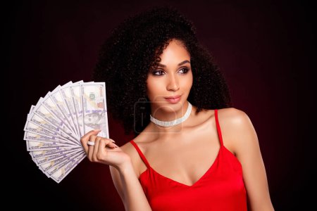 Téléchargez les photos : Photo de la gagnante de poker riche magnifique montrant l'argent isolé sur fond de couleur rouge foncé. - en image libre de droit