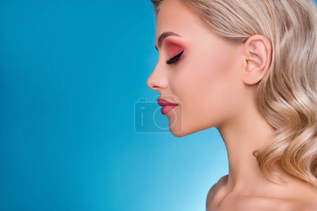 Photo for Profile side photo od lady in beauty salon treatment having her face make up over blue background. - Royalty Free Image