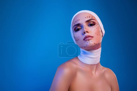 Téléchargez les photos : Photo de jolie fille magnifique en bandage médical chirurgie plastique patient sur fond bleu néon couleur. - en image libre de droit