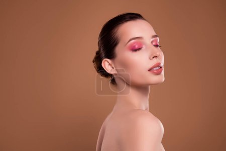 Foto de seductora dama caliente tiene procedimiento visagista en salón de belleza ojos cerrados para la aplicación de maquillaje brillante.