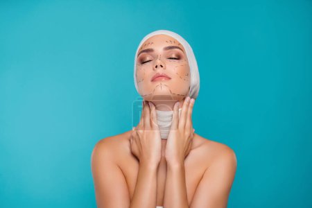 Foto de Foto de la señora en vendaje médico cuello táctil prepararse para la cirugía plástica aislado sobre fondo cian. - Imagen libre de derechos