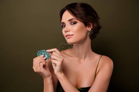Foto de Foto de atractiva señora elegante jugador de póquer mantenga fichas aisladas sobre fondo de color verde. - Imagen libre de derechos