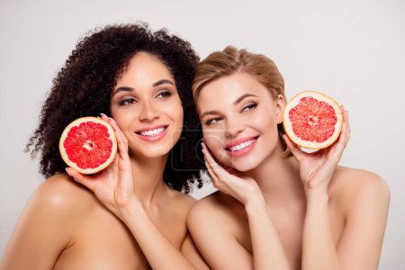 Foto de Foto de hermosas chicas impresionantes sostienen naranja fruta rebanada mirar sobre pegar espacio vacío fondo toque cara perfecta. - Imagen libre de derechos