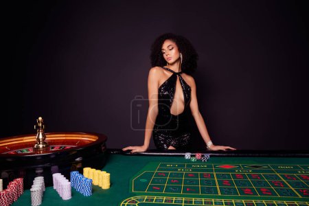 Téléchargez les photos : Photo de croupier dame magnifique attrayant dans la table debout club de poker de nuit se préparer pour le jeu risqué. - en image libre de droit