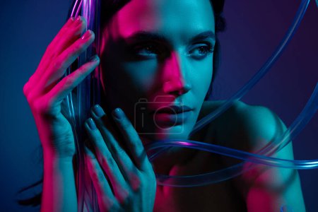 Téléchargez les photos : Gros plan photo de femme toucher des câbles de beauté en plastique regarder de côté isolé fond de couleur ultraviolette. - en image libre de droit