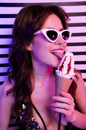 Photo for Vertical photo of pretty young girl hold lick sweet ice cream isolated on vintage striped neon light background. - Royalty Free Image