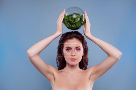 Téléchargez les photos : Photo de femme tenir sur la tête globe en verre avec des ingrédients biologiques végétaux isolé fond de couleur grise. - en image libre de droit
