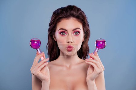 Portrait de belle fille modèle moussée lèvres baiser tenir verre cryothérapie bouteille d'outil isolé sur fond de couleur bleue.