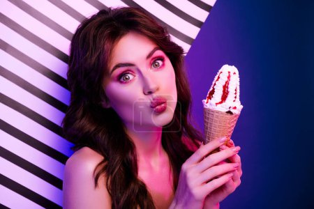 Photo portrait of lovely young lady amazed hold ice cream kiss isolated on retro striped neon gradient light background.