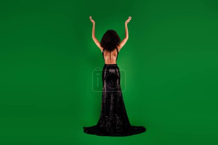 Photo for Rear view photo of glamour rich elegant lady posing with raised hands festive occasion over green color background. - Royalty Free Image