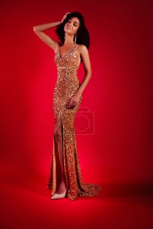 Photo for Photo of stunning rich lady president wife enjoy vogue ceremony wear glitter glowing evening gown over red background. - Royalty Free Image