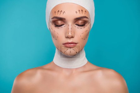 Photo for Photo of lady in bandage with drawing lines close eyes for face lifting plastic surgery over cyan background. - Royalty Free Image
