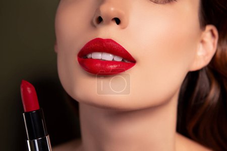 Photo for Cropped portrait of lady preparing for romantic date applying red glossy pomade on lips over khaki background. - Royalty Free Image