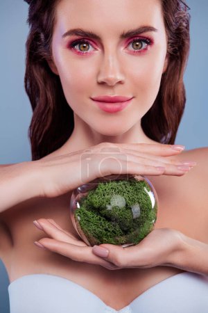 Téléchargez les photos : Photo de femme tenir globe en verre avec plante de mousse verte isolé sur fond de couleur pastel. - en image libre de droit