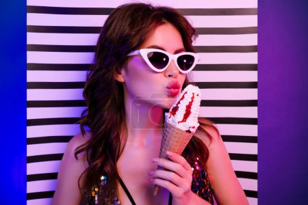 Photo for Photo portrait of attractive young woman kiss hold tasty ice cream isolated on retro striped neon light background. - Royalty Free Image