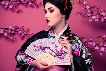 Téléchargez les photos : Portrait d'une femme chinoise sophistiquée vêtue de kimono traditionnel imprimé isolé sur fond rose. - en image libre de droit