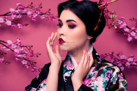 Téléchargez les photos : Photo de magnifique élégante femme coréenne geisha toucher sa peau beau visage isolé sur fond de couleur rose. - en image libre de droit