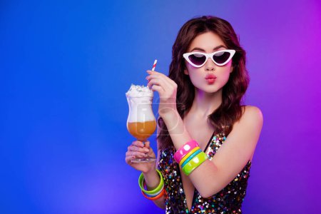 Téléchargez les photos : Portrait photo de jeune femme séduisante tenir cocktail profiter boisson baiser isolé sur fond néon lumière rétro. - en image libre de droit