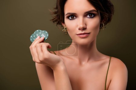 Foto de Retrato de chica atractiva elegante mantenga fichas de póquer apuestas aisladas sobre fondo de color verde. - Imagen libre de derechos
