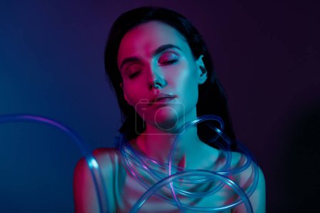 Téléchargez les photos : Photo de femme les yeux fermés attachés dans des câbles de beauté en plastique isolé brillant fond de couleur néon. - en image libre de droit