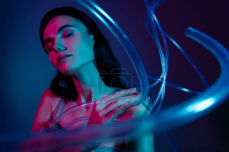 Foto de Foto de mujer con los ojos cerrados toque dedos hombro rodear cables de belleza de plástico aislado fondo ultravioleta. - Imagen libre de derechos