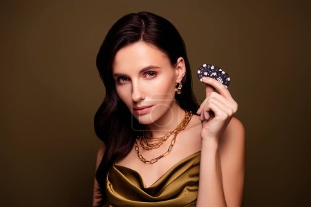Foto de Foto de elegante dama elegante jugador de póquer profesional mantenga fichas para otro juego de suerte de color marrón degradado fondo. - Imagen libre de derechos
