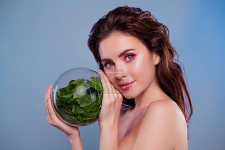 Téléchargez les photos : Photo de femme tenir la sphère de verre montrant des plantes vertes isolé fond de couleur grise. - en image libre de droit