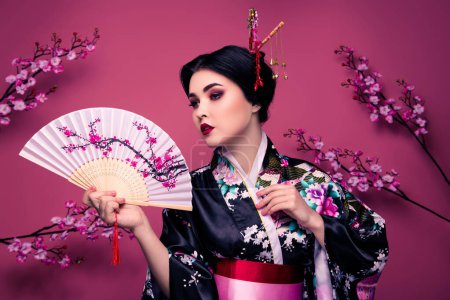 Téléchargez les photos : Photo de mignonne belle femme élégante en kimono exécutant la danse nationale isolé sur fond de couleur rose. - en image libre de droit
