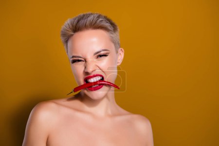 Foto de Foto de mordedura de mujer mantenga los dientes de chile rojo mirada peligrosa pastel aislado color marrón fondo. - Imagen libre de derechos