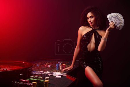 Foto de Foto de chic chica atractiva caliente mantenga billetes que muestran los jugadores de póquer premio por la victoria en el juego club de fiesta privada. - Imagen libre de derechos