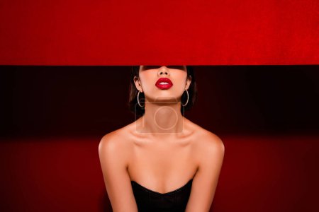 Photo for Photo of attractive chinese young woman hide face banner wear black leather clothes isolated on red color background. - Royalty Free Image