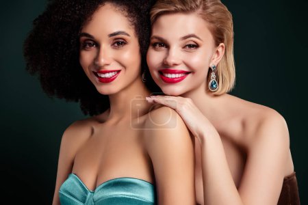 Téléchargez les photos : Photo de jolies filles joyeux avec des bijoux chers porter haut de style vogue souriant sur fond vert foncé. - en image libre de droit