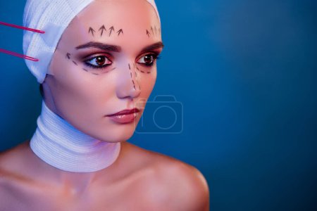 Photo for Photo of plastic surgery patient girl in facial medical bandage have tape tightening over neon blue color background. - Royalty Free Image