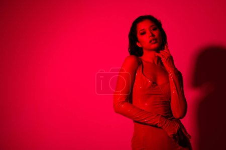 Foto de Foto de atractiva joven gallina caliente toque ella misma vestida ropa de cuero rojo aislado sobre fondo de luz de neón rojo. - Imagen libre de derechos