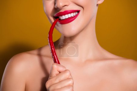 Photo for Cropped photo of smiling woman hold bite red spicy pepper isolated on yellow mustard color background. - Royalty Free Image