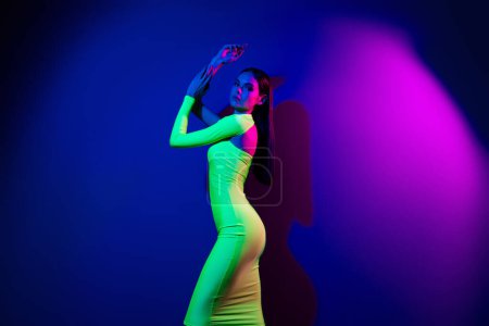 Téléchargez les photos : Profil portrait de confiant tendre modèle fille posant forme parfaite espace vide isolé sur fond de néon violet. - en image libre de droit