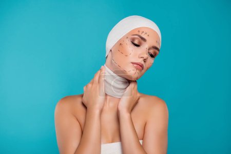 Photo for Photo of plastic surgery patient lady touch neck wrapped in medical bandage isolated over cyan background. - Royalty Free Image