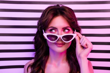 Photo for Photo of attractive young woman take off sunglass look empty space isolated on retro striped neon light background. - Royalty Free Image